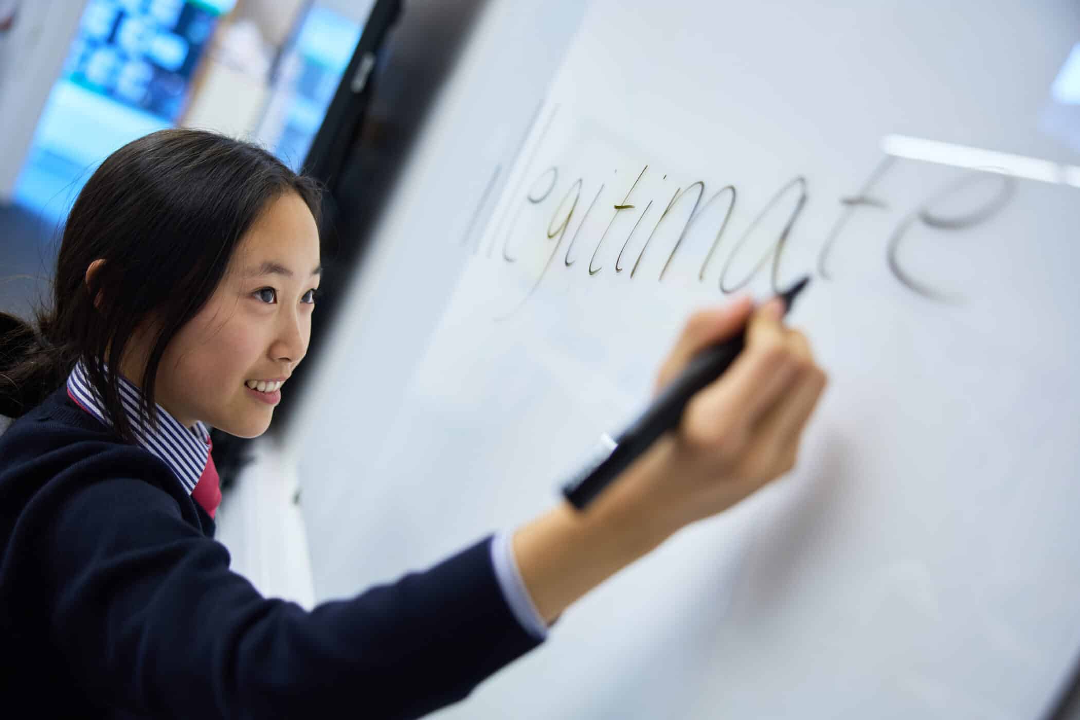 A female student in a school uniform is writing the word 