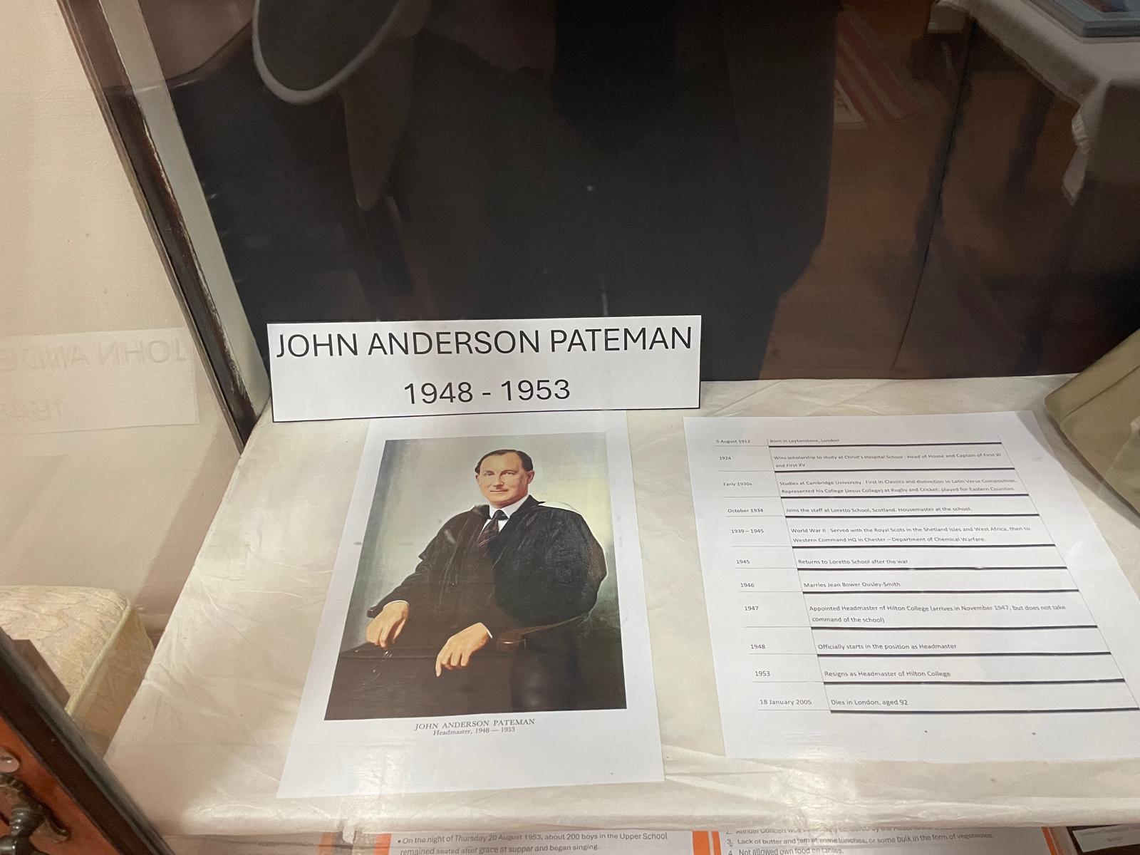 A museum display honoring John Anderson Pateman, with a printed portrait of him in a dark academic gown, a nameplate indicating his headmastership from 1948 to 1953, and a typed biography outlining key milestones in his life and career.