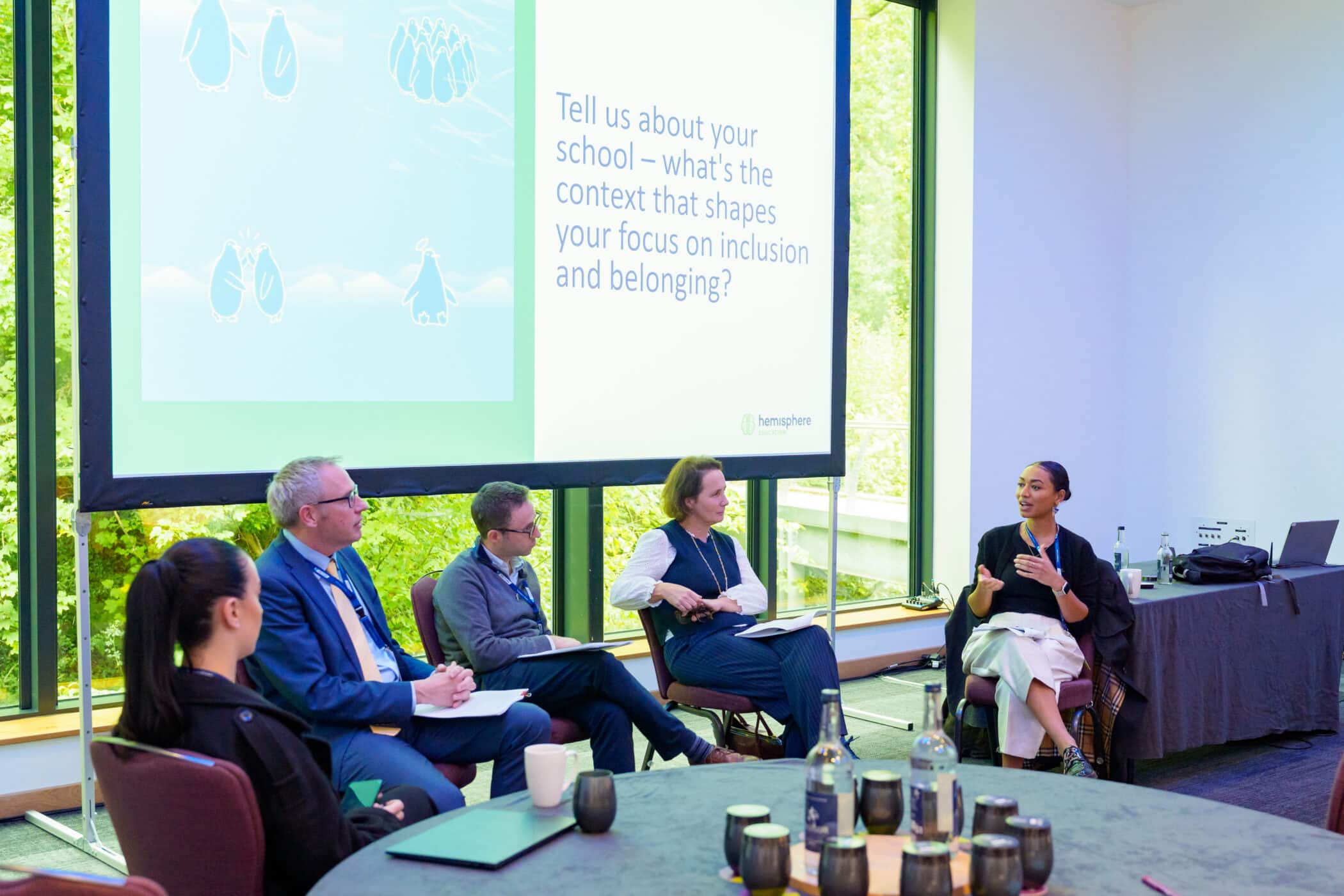 Panel discussion on inclusion and belonging at a conference, with four speakers seated in front of a presentation screen.