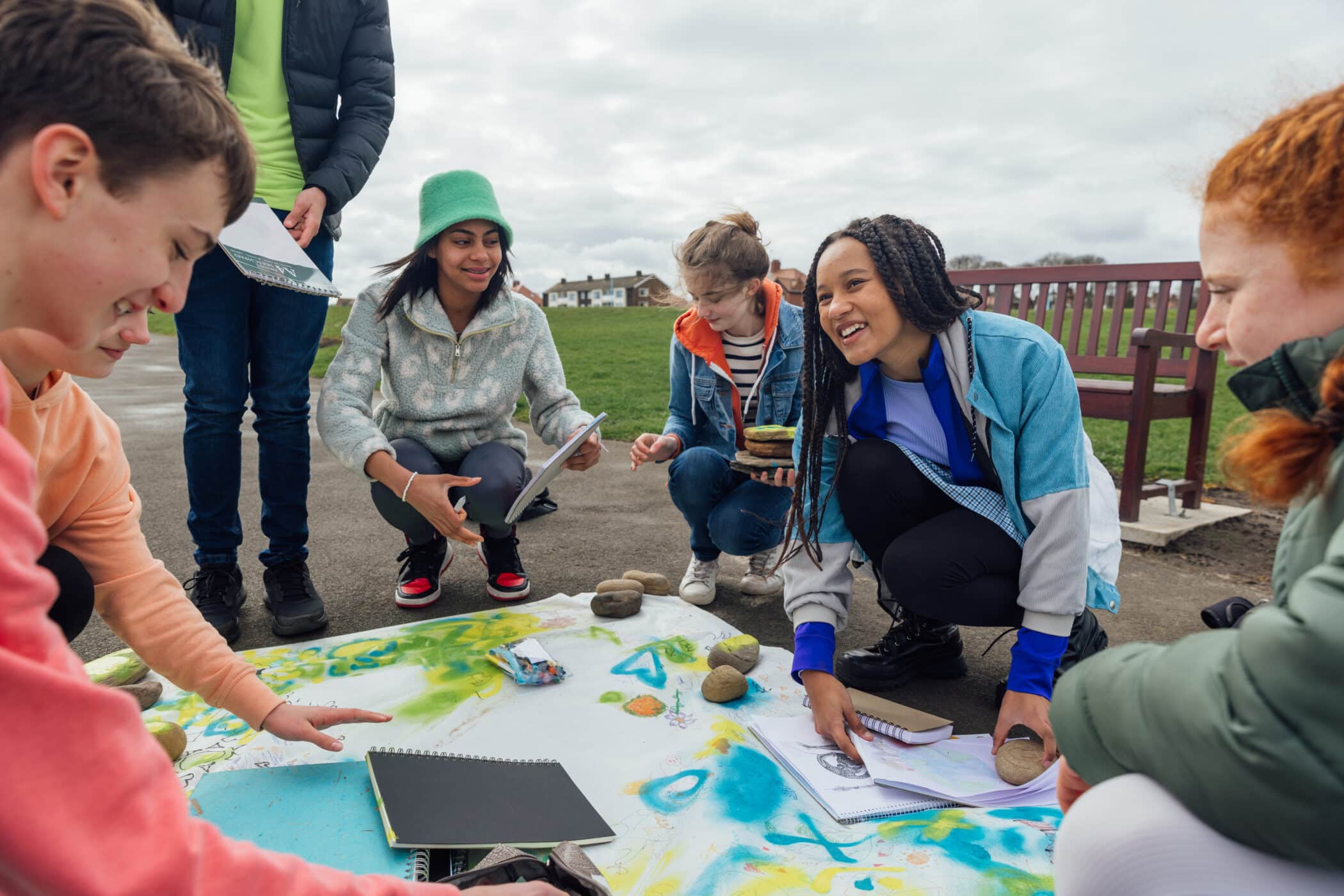 Students work together on an outdoor educational project using maps and notebooks.
